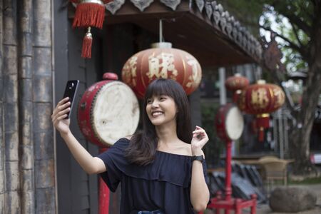 smiling young asian woman selfie with smart phone in China town