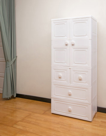 White plastic wardrobe with drawers on wooden floor in bedroom