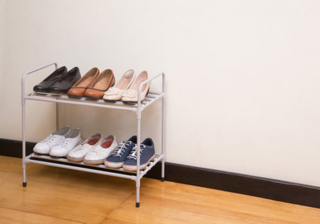 Small metal shoe shelf with women shoes on wooden floor in the roomの写真素材