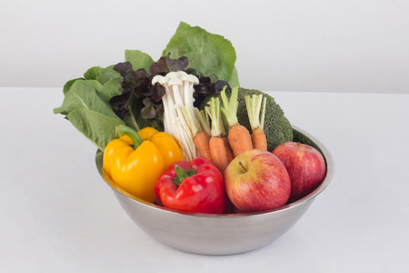 vegetables and fruits in stainless steel bowl isolated on white backgroundの写真素材