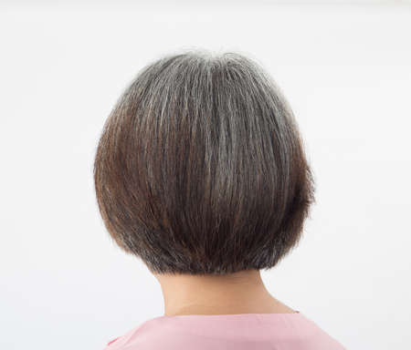Head of elderly woman tranforming to grey hair, from behind on white backgroundの写真素材
