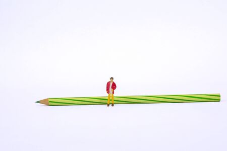 Miniature people is reflecting in front of green pencil isolated on white backgroundの写真素材