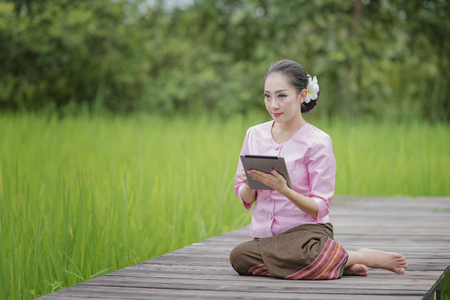 Beautiful girl is checking the quality of the rice fields with laptop,farmer girl in the rice fields.の写真素材