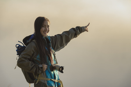 Adventures with morning fog,The adventurer stands at the top of the mountain with a foggy morning sky with the shadow of a distant mountain.の写真素材