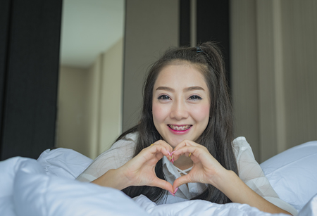 Pretty girl in love of Valentine's Day,sexy woman in pajamas posing against white bed.の写真素材