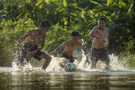 Children play soccer in the river.の写真素材
