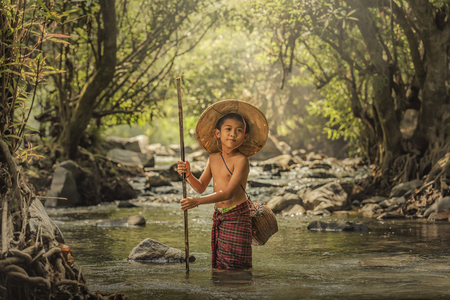 Little boy is fishing on the riverの写真素材