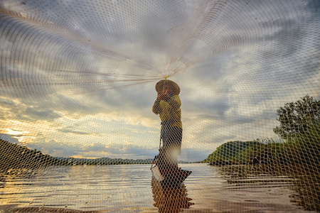 Fishermen fishing in the early morning golden light,Fishermen on a fishing boat.の写真素材