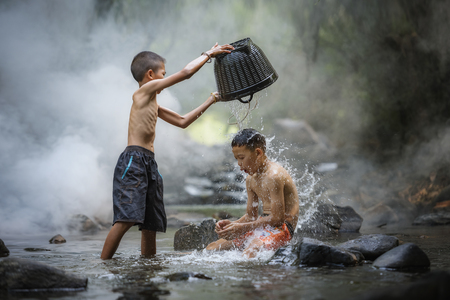 Portrait of Asian boy fisherman with waterfall in outdoors,Childrens  playing in the creek water happily,Children fishing in the river,The boys are enjoying playing the stream,Asian boy,Asian Childrenの写真素材