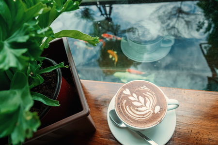 Hot coffee on the wooden table and the mountain view background,cup of coffee with pattern on wooden background.の写真素材