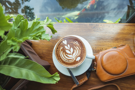 Hot coffee on the wooden table and the mountain view background,cup of coffee with pattern on wooden...