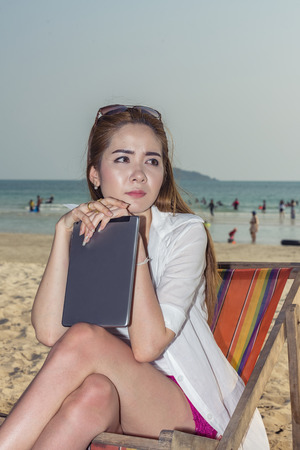 Woman working on laptop at the beach.の写真素材