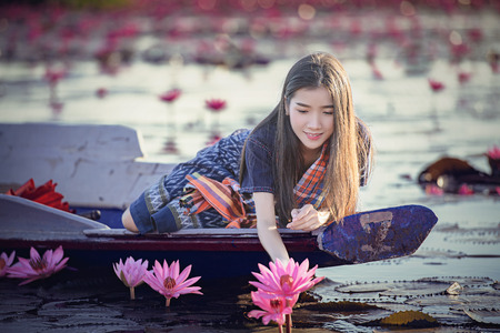Picture of beautiful Laos woman with lotus flower,young woman relaxing with beautiful lotus flower field at the Red Lotus Sea, Bua Daeng, Udon Thani,Morning Sea of Red Lotus,Unseen nature in Thailand.の写真素材