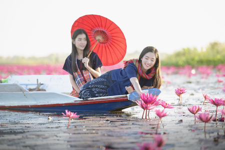 Picture of beautiful Laos woman with lotus flower,young woman relaxing with beautiful lotus flower field at the Red Lotus Sea, Bua Daeng, Udon Thani,Morning Sea of Red Lotus,Unseen nature in Thailand.の写真素材