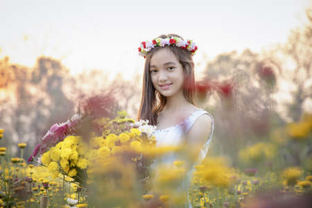 Beautiful girl in vintage dress and hat standing near colorful flowers.Beautiful romantic young woman of flowers posing on a background.Inspiration of spring and summer.Perfume.Art of romantic woman.の写真素材