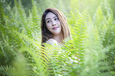 Portrait of young beautiful woman with perfect smooth skin in tropical leaves. woman in seasons spring leaves.  beautiful girl turning in green fresh summer gown. Enjoying the nature.の写真素材