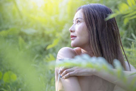 Portrait of young beautiful woman with perfect smooth skin in tropical leaves. woman in seasons spring leaves.  beautiful girl turning in green fresh summer gown. Enjoying the nature.の写真素材
