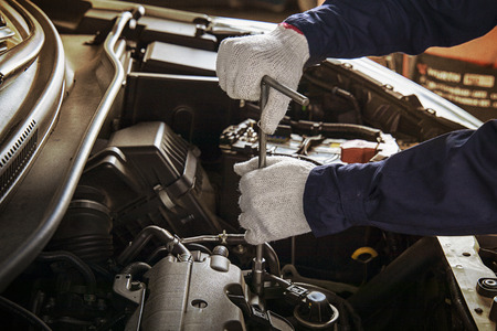 Hands of car mechanic with wrench in garage.Auto mechanic working in auto repair service.Repair service.Car repair and maintenance.の写真素材