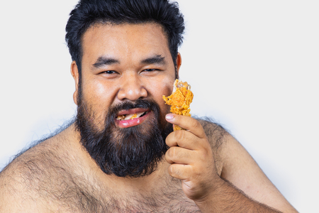 Fat men on a white background. Fat man with a big belly. Fat man eat a lot of food,Fat man eat fried chicken. extra weight, diet.の写真素材