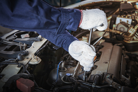 Hands of car mechanic with wrench in garage.Auto mechanic working in auto repair service.Repair service.Car repair and maintenance.の写真素材