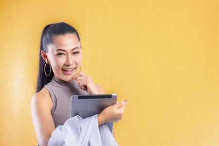 Woman working on laptop at office while talking on phone, Portrait of confident young woman working in her office with mobile phone. Working woman with colorful background.の写真素材