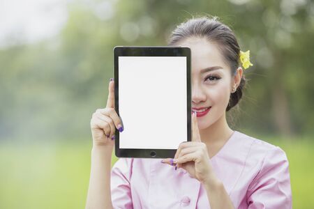 Beautiful woman taking picture of herself at the beachgarden,Woman working on laptop in field.の写真素材