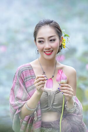 Picture of beautiful woman with lotus flower, Young beautiful woman relaxing with lotus flower, The girl holds the lotus flower in the field.の写真素材