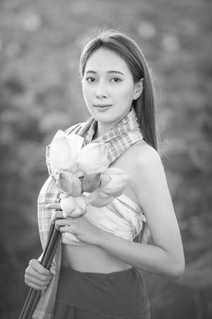 Picture of beautiful woman with lotus flower, Young beautiful woman relaxing with lotus flower, The girl holds the lotus flower in the field.の写真素材