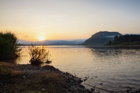 The morning sunrise over the river and the foggy mountains. Independent travel concept with beautiful nature.の写真素材