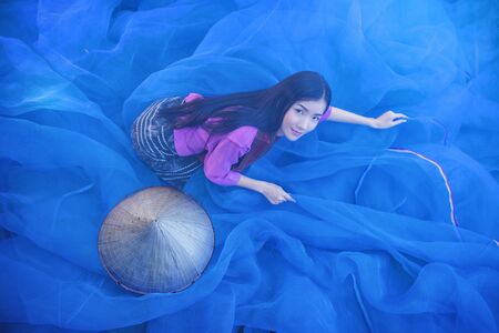 women are sewing nets in farmer village,Vietnamese women repair fishing net.の写真素材