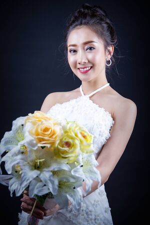 Portrait of a beautiful asian woman smiling brightly at the camera. Natural female in bride dress concept.の写真素材