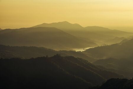 Sunrise and fog on the mountain. Sunlight with the sun's rays illuminate the beautiful mountain.の写真素材