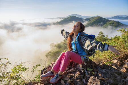 Tourists with fog on the top of the hill. Travelers breathe fresh air while photographing the beautiful sunrise and mist.の写真素材