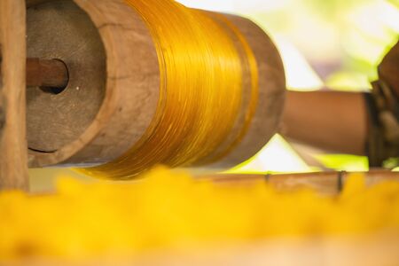 Wheel Spinning Yarn with Yellow Thread to work for Weaving machine and Thai traditional Silk. Artists artisans handicrafts handmade manufacturing motton silk hand loom Thai. の写真素材