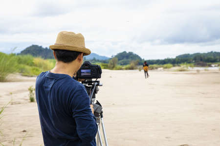 Photographer to pay close attention to take a photo. Photographer taking music video nature of river and mountain landscape.の写真素材
