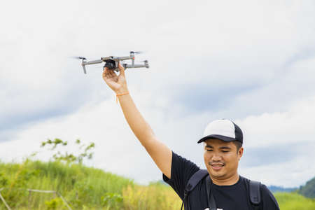 Man operating a drone with remote control. Drone with high resolution digital camera on the river and sky.の写真素材