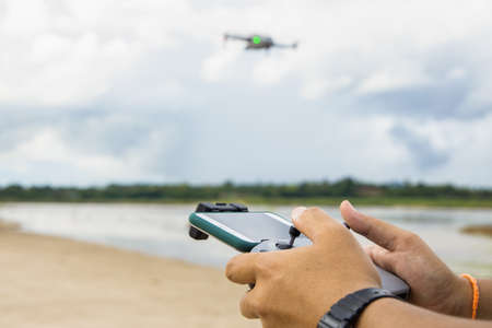 Man operating a drone with remote control. Drone with high resolution digital camera on the river and sky.の写真素材