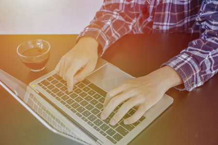 Learn online, Student watching lesson online and studying from home. Young man taking notes while looking at computer screen following professor on video call. Studying from home on pc.の写真素材