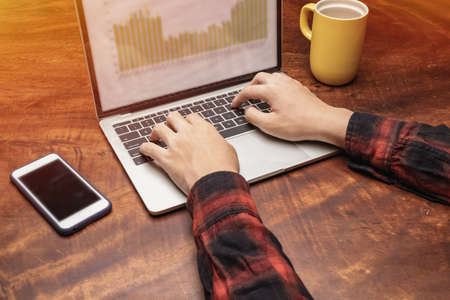 Learn online, Student watching lesson online and studying from home. Young man taking notes while looking at computer screen following professor on video call. Studying from home on pc.の写真素材