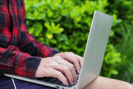 Learn online, Student watching lesson online and studying from home. Young man taking notes while looking at computer screen following professor on video call. Studying from home on pc.の写真素材