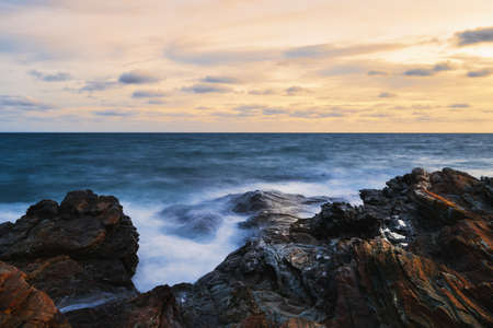 Seaside rocks, Waves hitting the rocks by the sea against the sunset.の写真素材