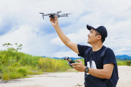 Man operating a drone with remote control. Drone with high resolution digital camera on the river and sky.の写真素材