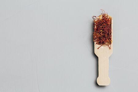 Saffron spices in brown wooden spoon on gray background. Flat lay. Copy spacy.の写真素材