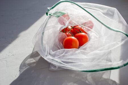 Tomatoes in a reusable bag on a concrete background. Zero waste concept. Plastic free concept....