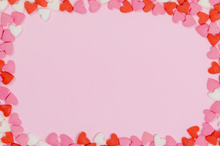 Heart shaped candies scattered on pink background love wedding concept. Valentines day pattern background. Flat lay top view. Copy spaceの写真素材