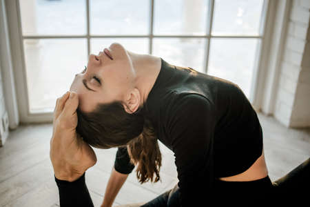 Attractive slim fit yoga girl doing yoga or fitness exercises in a yoga studio. Sport and recreation...