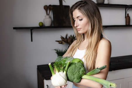 fitness woman holds raw green vegetablesの写真素材