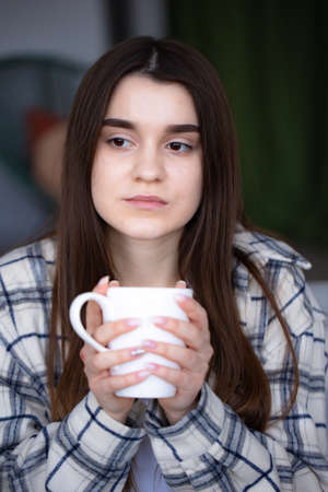 Thoughtful women sitting in couch with coffee. Woman have relax Enjoying quiet lifestyle indoor at home with cup of tea. Close upの写真素材