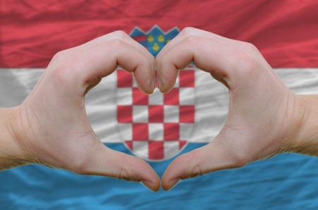 Gesture made by hands showing symbol of heart and love over Croatian flagの写真素材