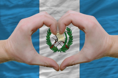 Gesture made by hands showing symbol of heart and love over guatemala flagの写真素材